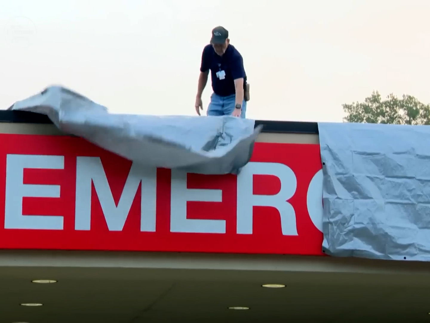 A worker covering up the ER entrance of a recently-closed hospital